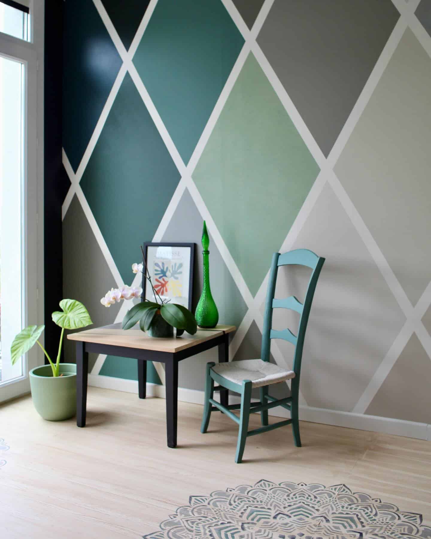 Décoration murale à losanges vert et gris style moderne Mur avec losanges peints en vert et gris, mobilier en bois, chaise bleue et affiche Matisse décorative.